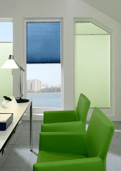 Plissee Büro Grüne Sessel an Schreibtisch vor Fenster mit grünen und blauen Plissees